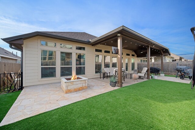 rear view of property featuring a patio area, ceiling fan, a yard, and an outdoor fire pit