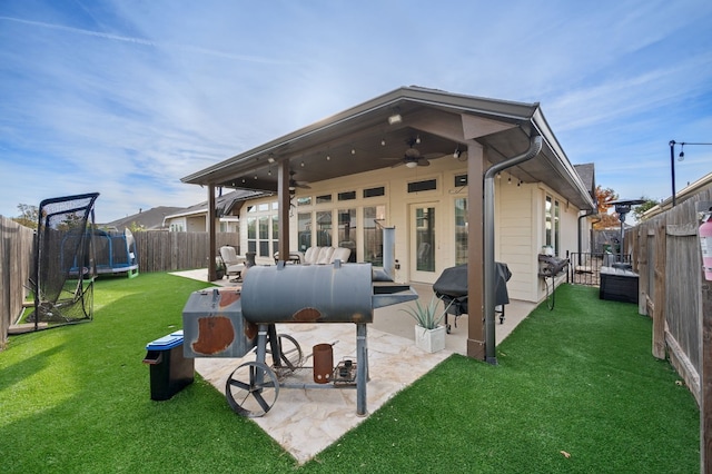 back of house with a lawn, a trampoline, an outdoor hangout area, ceiling fan, and a patio area