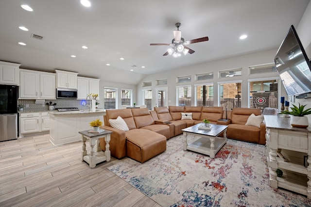 living room with light wood-type flooring, ceiling fan, and lofted ceiling