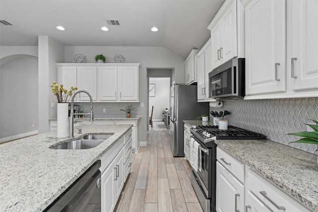 kitchen featuring light stone countertops, tasteful backsplash, stainless steel appliances, sink, and white cabinetry