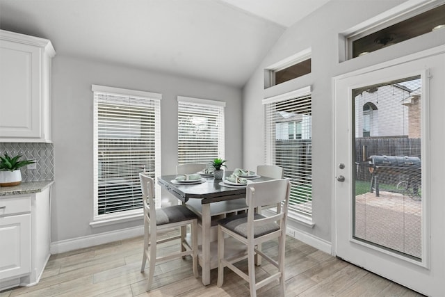 dining room featuring lofted ceiling and light hardwood / wood-style flooring