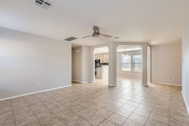 tiled empty room with ceiling fan with notable chandelier