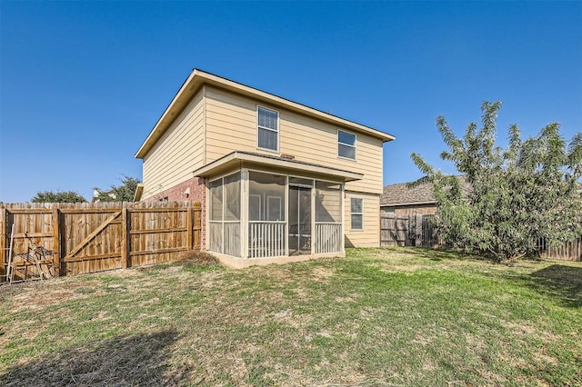 rear view of house featuring a sunroom and a yard