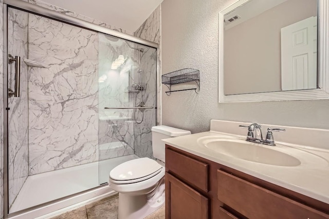 bathroom featuring tile patterned floors, vanity, a shower with shower door, and toilet