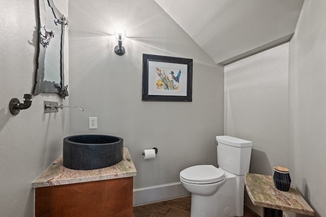 bathroom featuring vanity, toilet, wood-type flooring, and vaulted ceiling