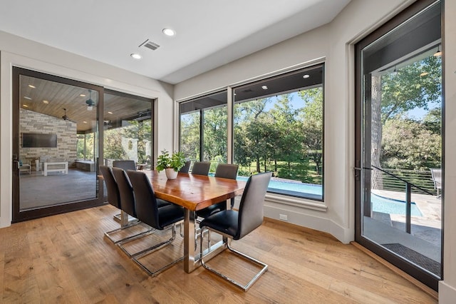 dining space featuring a wealth of natural light, vaulted ceiling, and light wood-type flooring