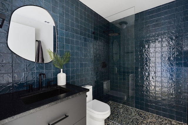 bathroom with tiled shower, vanity, tile walls, and backsplash