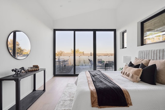 bedroom with light hardwood / wood-style floors, access to exterior, vaulted ceiling, and multiple windows