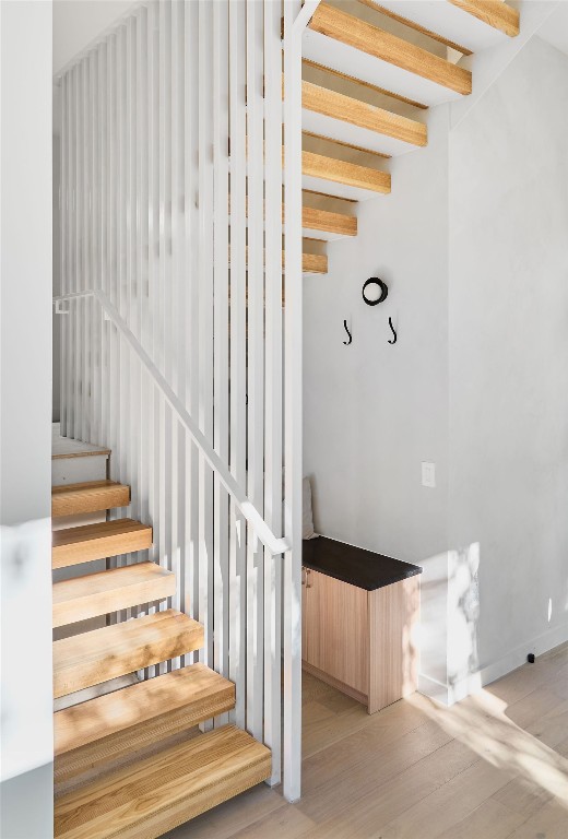 stairs with beam ceiling and hardwood / wood-style flooring