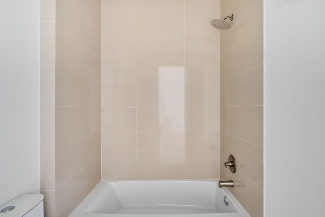 bathroom featuring toilet and tiled shower / bath