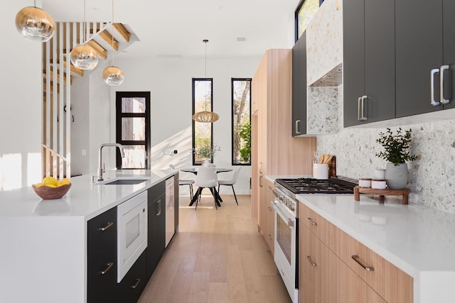 kitchen featuring pendant lighting, sink, an island with sink, light brown cabinetry, and stainless steel appliances