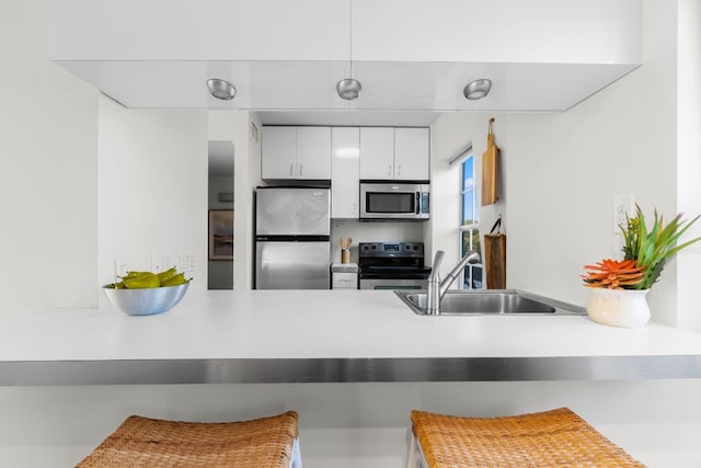 kitchen with white cabinets, appliances with stainless steel finishes, a breakfast bar area, and sink