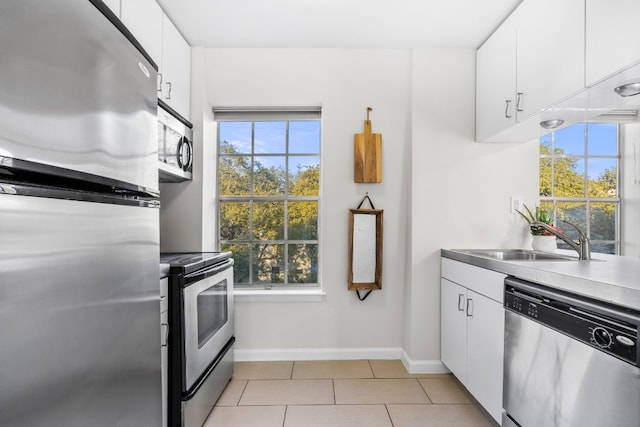 kitchen with white cabinets, stainless steel appliances, light tile patterned flooring, and sink