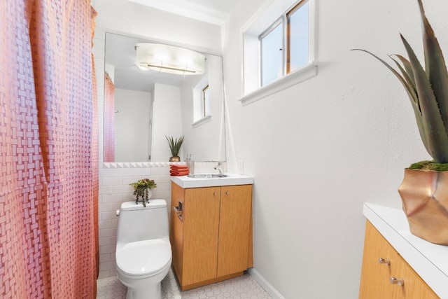 bathroom featuring tile patterned flooring, vanity, toilet, and tile walls