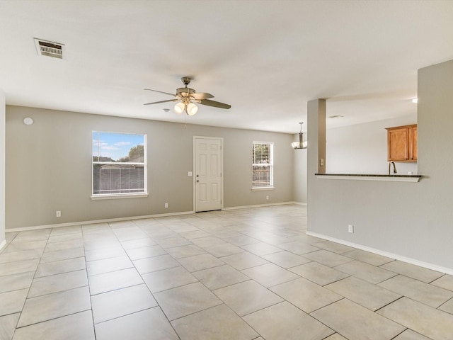 unfurnished living room with ceiling fan with notable chandelier and light tile patterned flooring