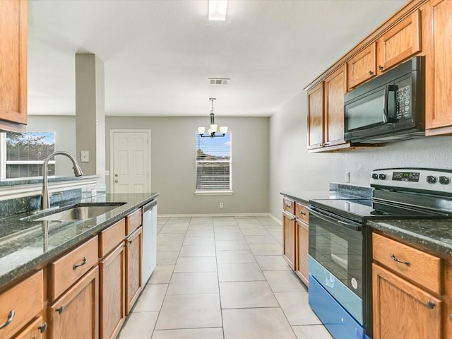 kitchen with decorative light fixtures, stainless steel appliances, dark stone countertops, an inviting chandelier, and sink