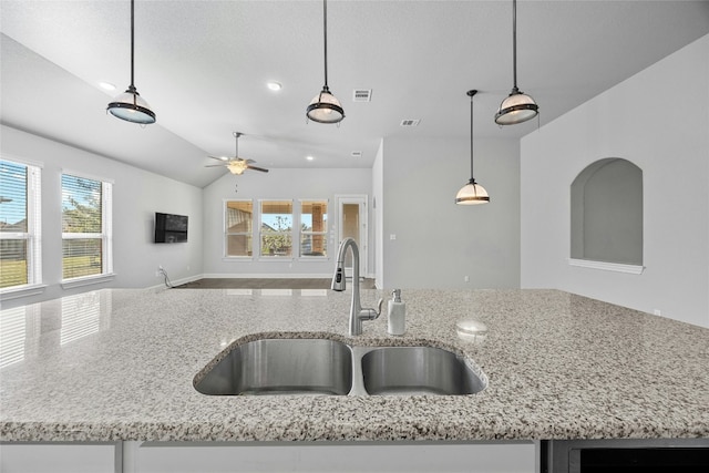 kitchen featuring lofted ceiling, sink, a kitchen island with sink, and decorative light fixtures