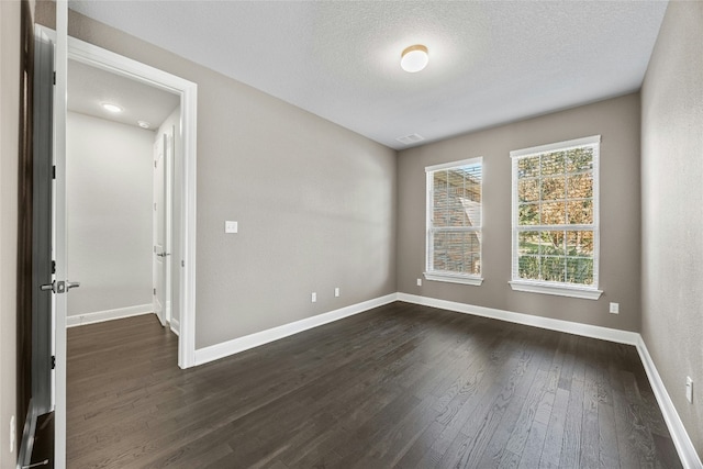 empty room with a textured ceiling and dark hardwood / wood-style floors