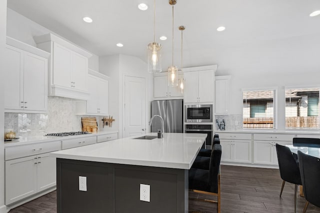 kitchen featuring sink, decorative light fixtures, a kitchen island with sink, white cabinets, and appliances with stainless steel finishes