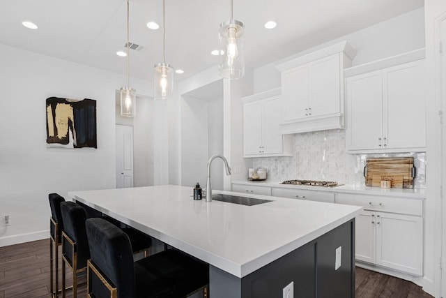 kitchen with decorative light fixtures, white cabinetry, a kitchen island with sink, and sink