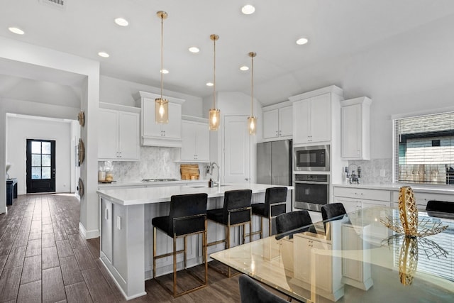 kitchen featuring white cabinetry, a large island, dark wood-type flooring, hanging light fixtures, and appliances with stainless steel finishes