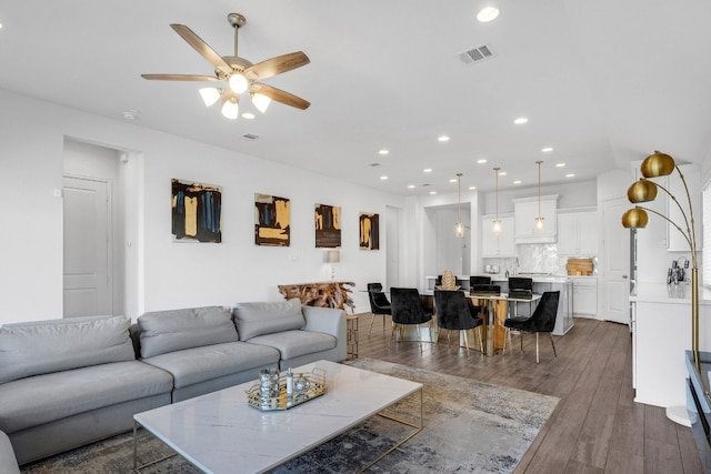 living room featuring ceiling fan and dark wood-type flooring