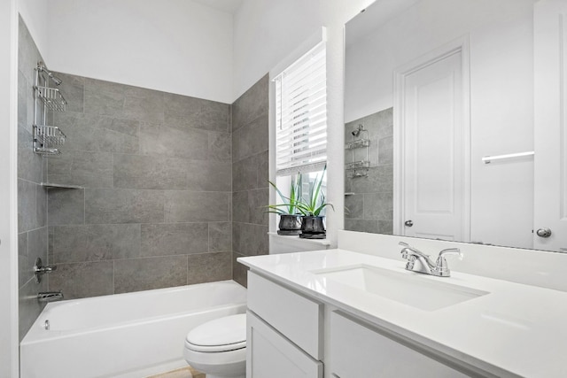 full bathroom featuring vanity, tiled shower / bath combo, and toilet