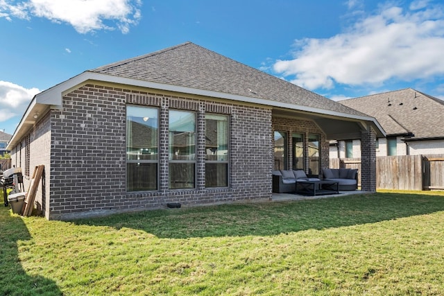 back of property with an outdoor living space, a patio area, and a lawn