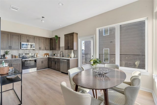 kitchen featuring decorative backsplash, sink, stainless steel appliances, and light hardwood / wood-style floors