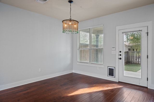 unfurnished dining area with a chandelier and dark hardwood / wood-style floors