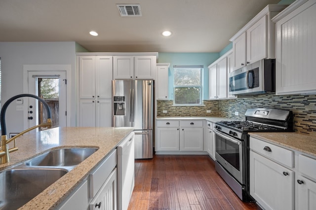 kitchen with stainless steel appliances, white cabinetry, and dark wood-type flooring