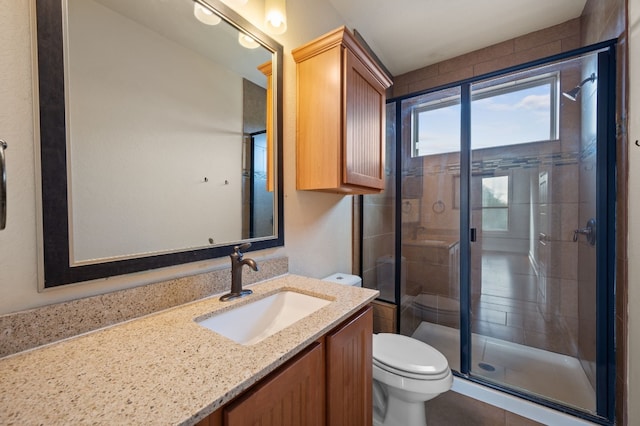 bathroom with walk in shower, vanity, and toilet