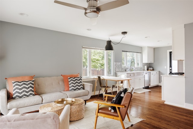 living room featuring hardwood / wood-style flooring, ceiling fan, and sink