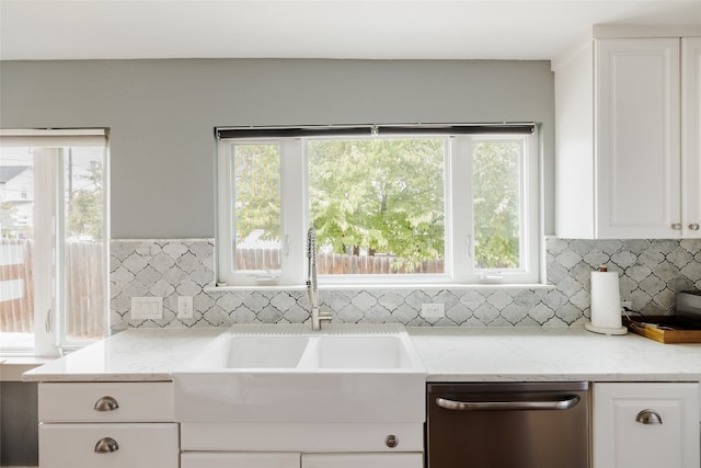 kitchen featuring stainless steel dishwasher, a wealth of natural light, and light stone counters