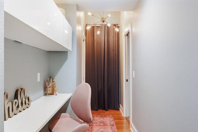 home office featuring light hardwood / wood-style floors and a chandelier