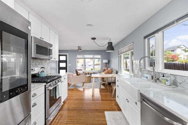 7611 Providence Ave Unit A, Austin, TX 78752 - kitchen featuring appliances with stainless steel finishes, light countertops, tasteful backsplash, light wood-style flooring, and white cabinets