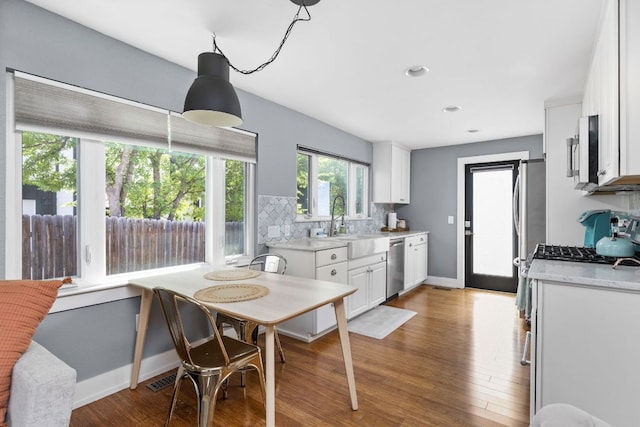 7611 Providence Ave Unit A, Austin, TX 78752 - kitchen with appliances with stainless steel finishes, white cabinetry, light countertops, wood finished floors, and decorative backsplash