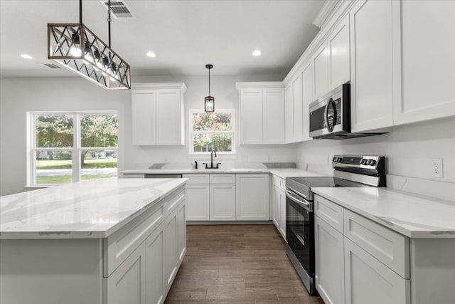 kitchen featuring white cabinets, stainless steel appliances, hanging light fixtures, and a healthy amount of sunlight