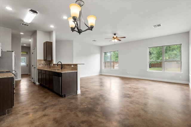 kitchen featuring light stone countertops, dark brown cabinetry, stainless steel appliances, sink, and pendant lighting