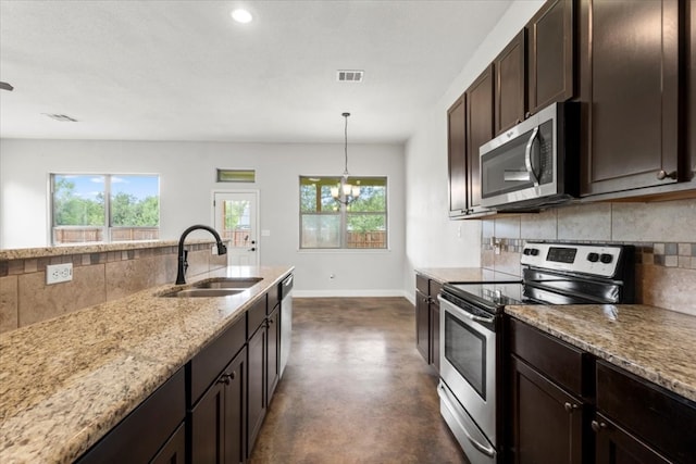 kitchen with sink, hanging light fixtures, light stone counters, a chandelier, and appliances with stainless steel finishes