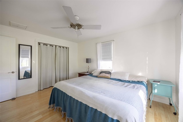 bedroom with ceiling fan, light wood-type flooring, and multiple windows