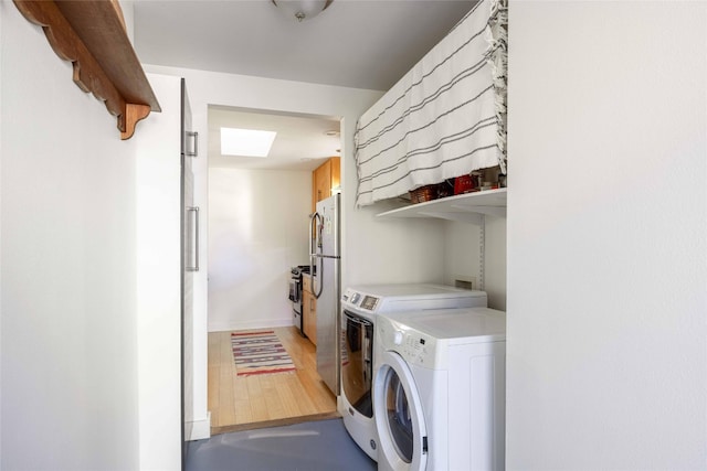 clothes washing area with separate washer and dryer and hardwood / wood-style floors