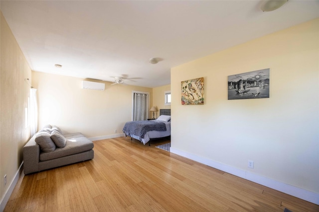 bedroom featuring light hardwood / wood-style flooring, ceiling fan, and a wall unit AC