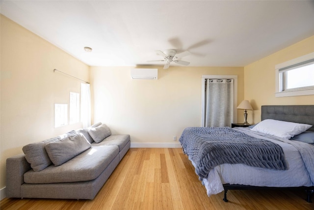 bedroom featuring ceiling fan, light hardwood / wood-style floors, and a wall mounted air conditioner