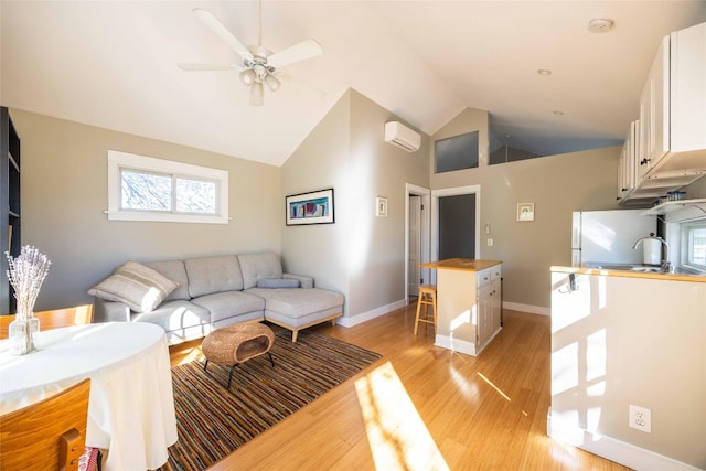 living room featuring a wall mounted air conditioner, ceiling fan, sink, high vaulted ceiling, and light hardwood / wood-style flooring