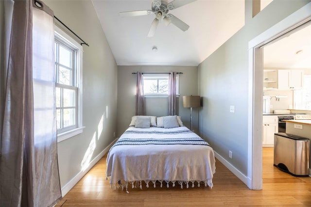 bedroom with ceiling fan, light wood-type flooring, lofted ceiling, and ensuite bathroom