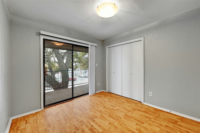 unfurnished bedroom featuring a closet, wood-type flooring, and access to outside