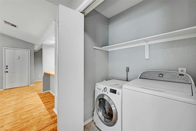 laundry area with separate washer and dryer and light hardwood / wood-style flooring