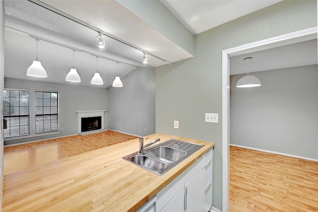 kitchen featuring decorative light fixtures, sink, and light wood-type flooring