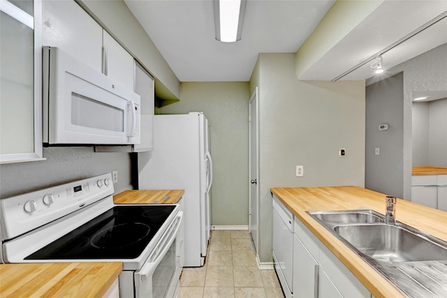 kitchen with sink, white appliances, white cabinets, and wooden counters